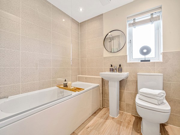 Modern bathroom with a bath and shower screen, pedestal basin, WC and contemporary wall tiles.