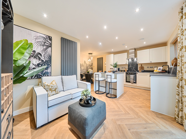 Open-plan lounge area with sofa, artwork and view into kitchen space.