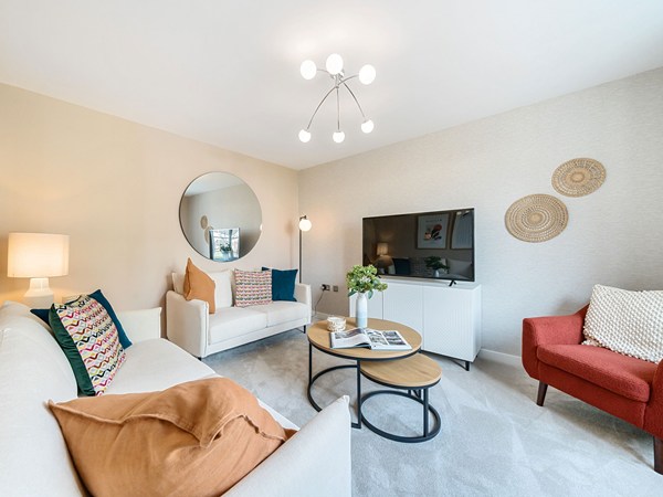 Bright living room with two sofas, an accent chair, coffee tables, feature lighting and a wall-mounted TV.