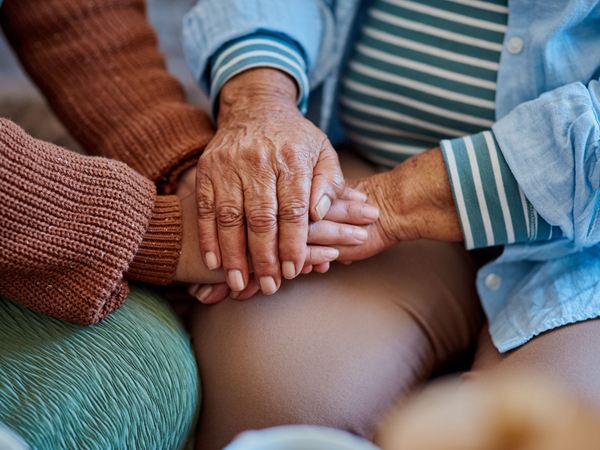 A close up image of a mother and a daughter holding hands.