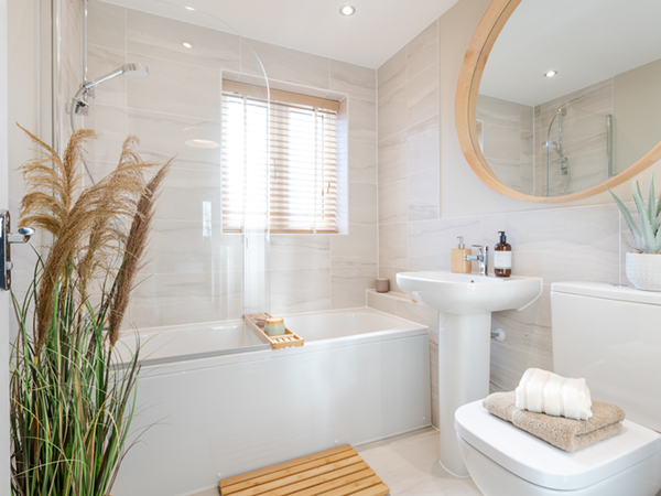Main family bathroom with cream tiles and white sanitaryware including a bath with overhead shower, sink and toilet