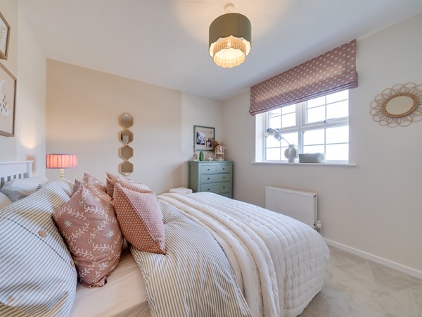 Bedroom 2 with a double bed, cream painted walls, pink printed blinds and green chest of drawers