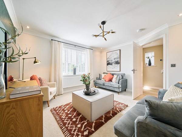 Bright living room with grey sofas, modern décor and large window at Persimmon Homes The Maples, Spalding, Lincolnshire.