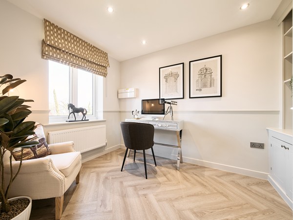 Home-office-with-built-in-shelving-stylish-desk-herringbone-flooring-and-view-to-hallway-and-stairs.