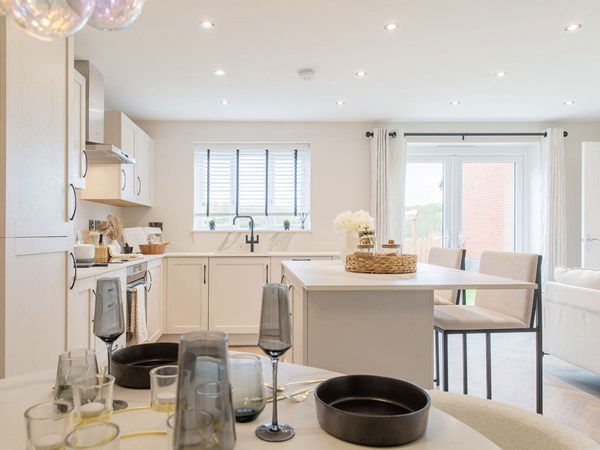 Contemporary kitchen with an island, shaker-style units, dining area and French doors opening to the garden.
