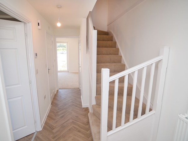 Hallway with staircase and wood-effect flooring in The Whinfell at Trehenlis Gardens.