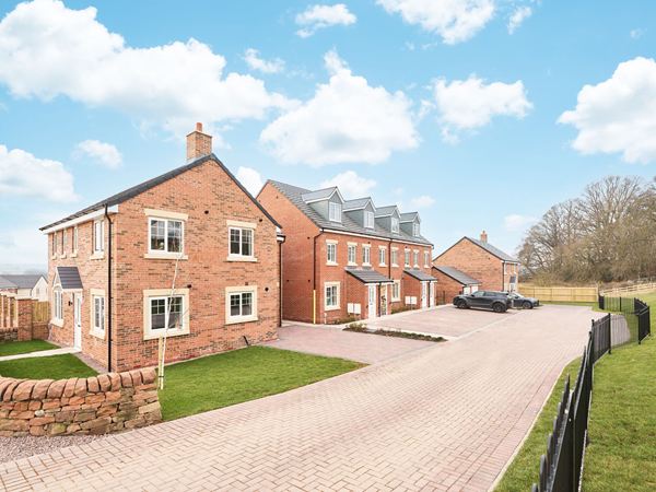 A small cul-de-sac of modern Persimmon homes against a blue sky with white clouds.