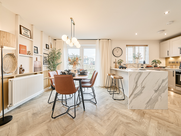 Open-plan kitchen and dining space with marble island, leather chairs, and decorative shelving.