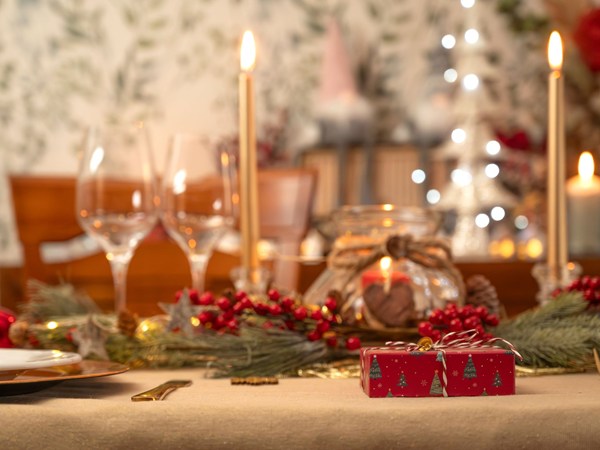 A lovely dining table decorated for Christmas with candles, glasses, and presents. 