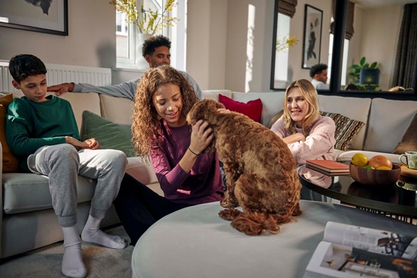 Family of four playing with dog in modern living room