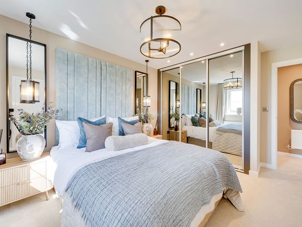 Double bedroom in The Burnham at Bluebell Meadow with blue feature cushions and neutral décor.