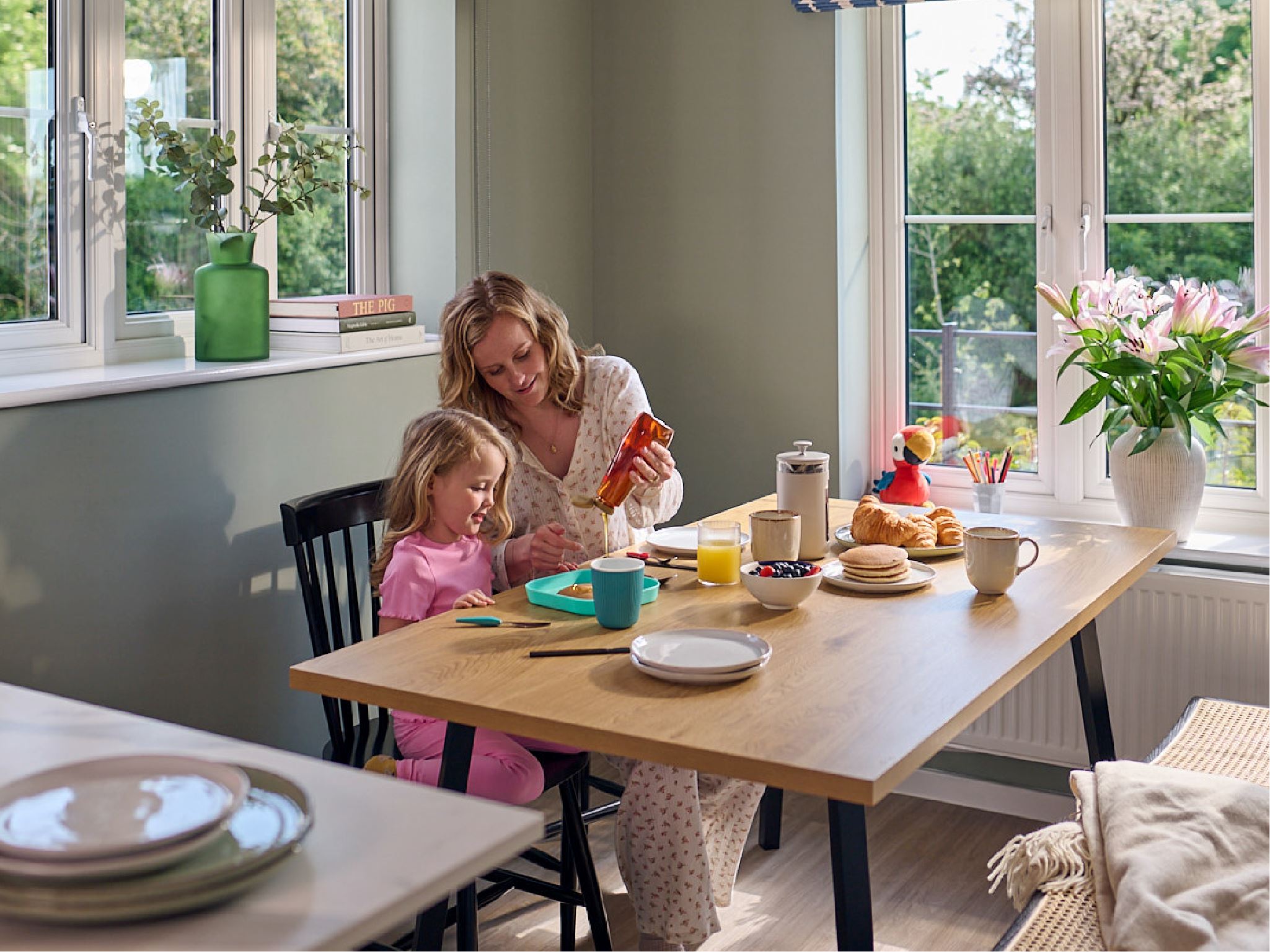 A mother and daughter sitting at a dining table in a modern Persimmon home.